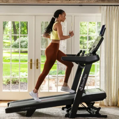 Woman running on BowFlex treadmill indoors near garden doors