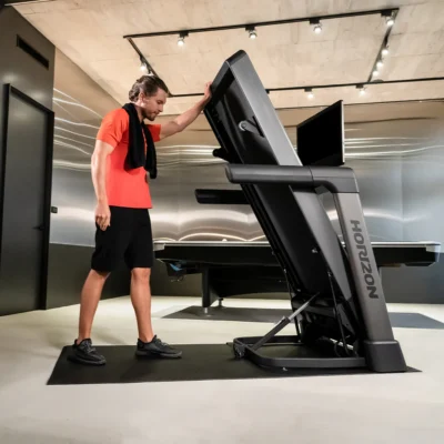 Man folding Horizon treadmill in modern gym space