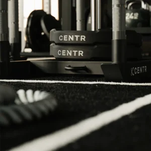 CENTR branded weight plates on gym floor with battle ropes