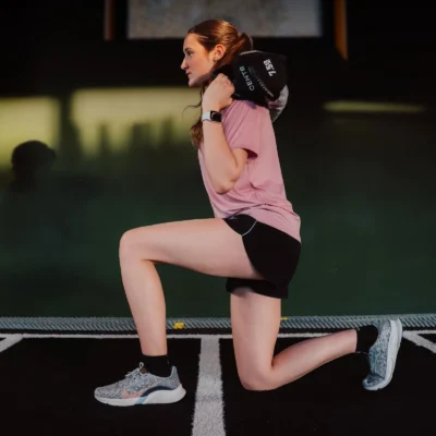centr x hyrox youngstars | 7.5kg competition sandbag Woman performing weighted lunge with sandbag in gym
